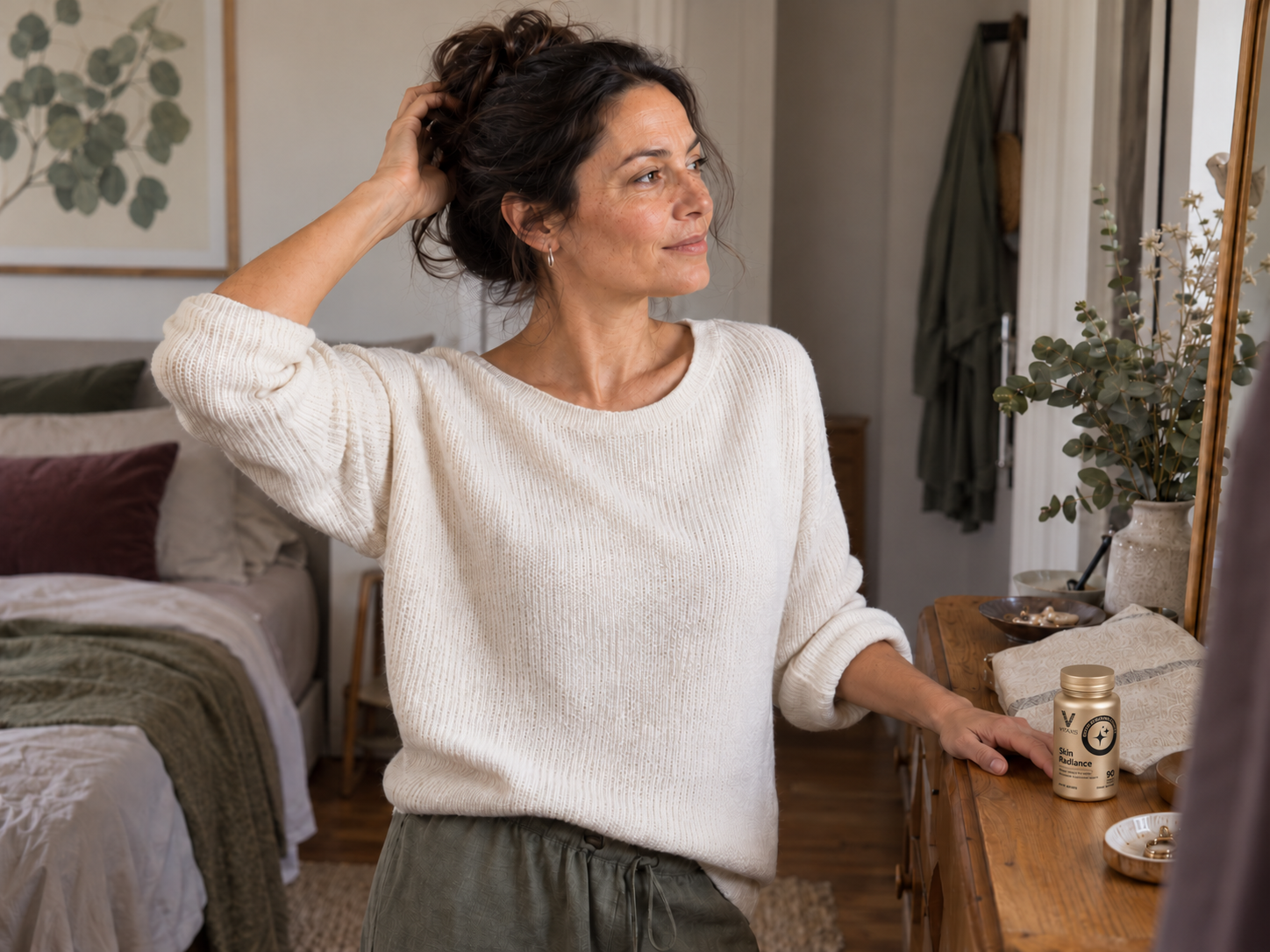 A woman at her dresser with a small VITAXIS Skin Radiance bottle among everyday belongings