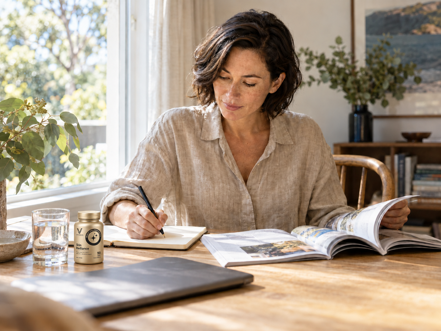 A woman reading and taking notes beside a smaller VITAXIS Skin Radiance bottle